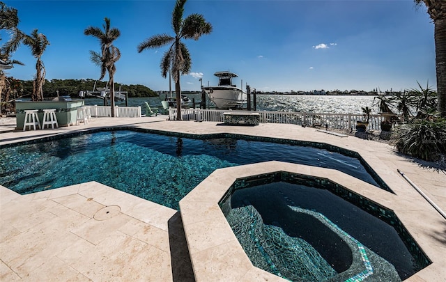 view of swimming pool featuring an in ground hot tub, a water view, a patio area, and a bar