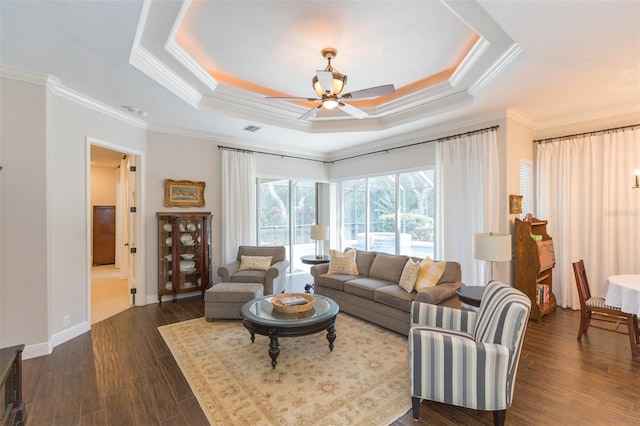 living room featuring dark wood-type flooring, ceiling fan, crown molding, and a tray ceiling