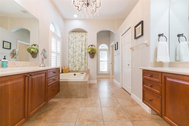 bathroom with a chandelier, vanity, a wealth of natural light, and a relaxing tiled tub