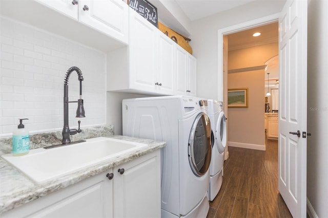 clothes washing area with dark hardwood / wood-style flooring, sink, cabinets, and washing machine and clothes dryer