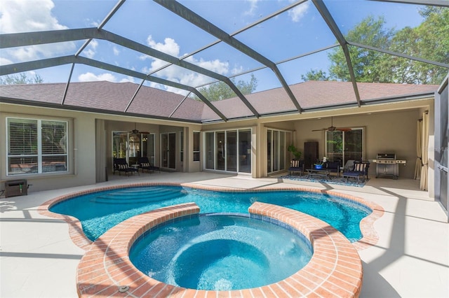 view of swimming pool featuring glass enclosure, ceiling fan, a patio, and an in ground hot tub