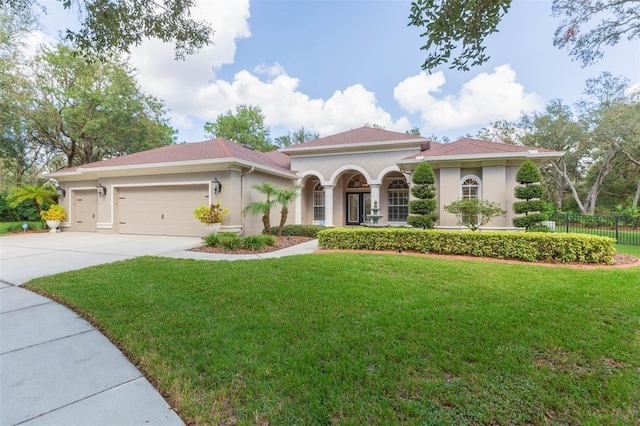 mediterranean / spanish house featuring a garage and a front yard