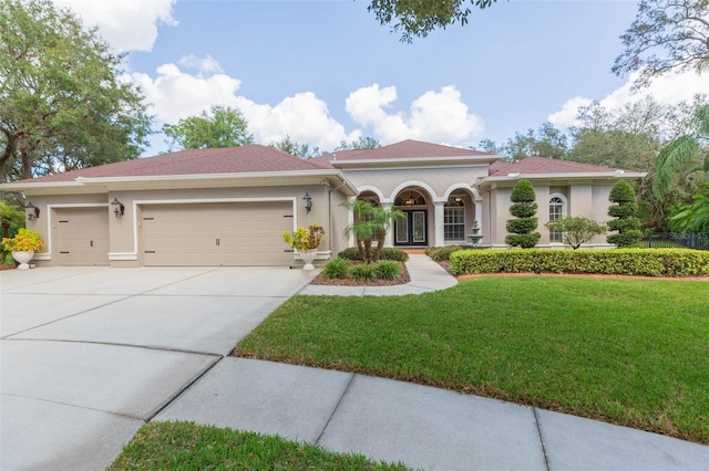 mediterranean / spanish home with a garage and a front lawn