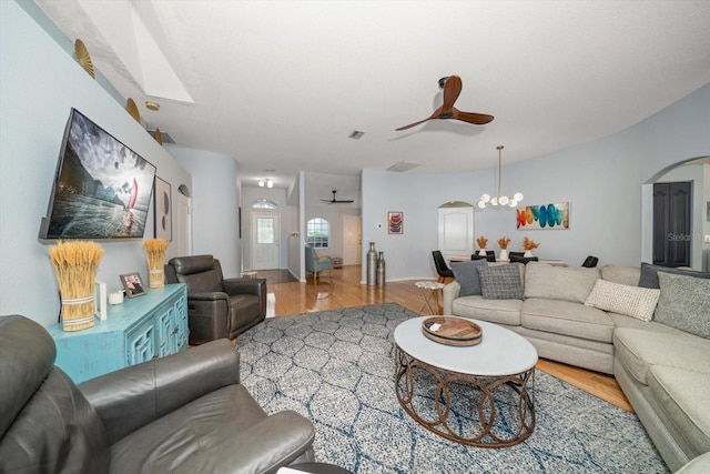 living room with ceiling fan with notable chandelier and light hardwood / wood-style flooring