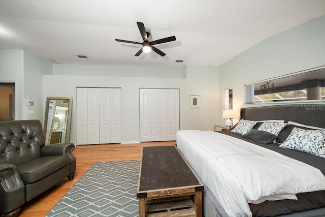 bedroom with ceiling fan, light hardwood / wood-style flooring, and multiple closets