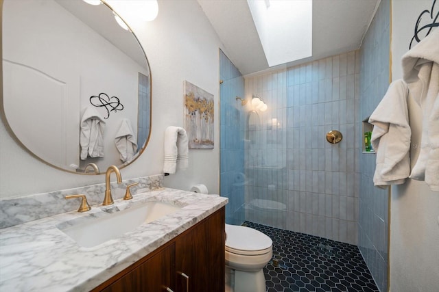 bathroom featuring toilet, vanity, a skylight, and tiled shower