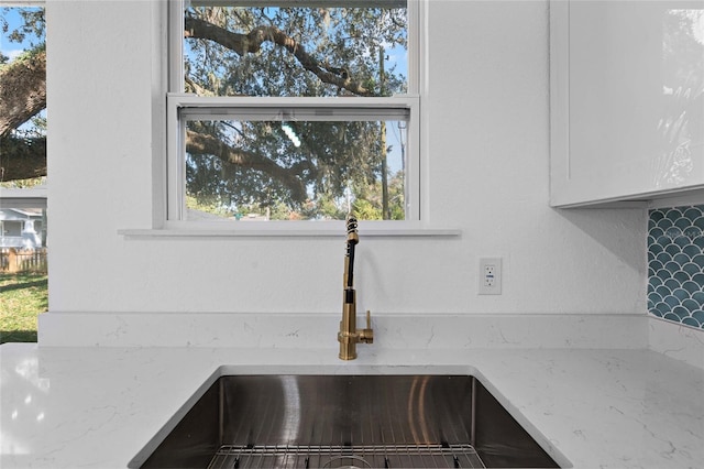 interior details with light stone countertops, white cabinetry, and sink