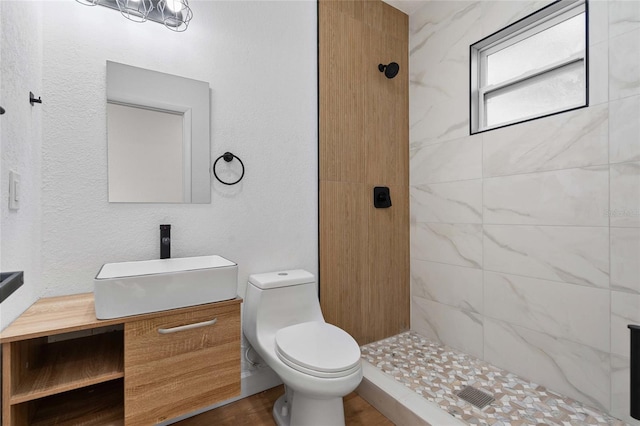 bathroom with vanity, toilet, and tiled shower