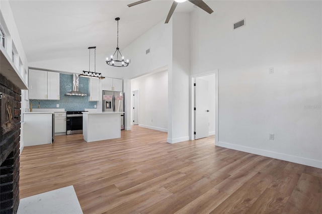 kitchen with appliances with stainless steel finishes, backsplash, decorative light fixtures, a center island, and white cabinetry