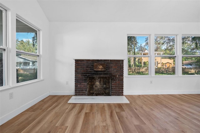 unfurnished living room with light hardwood / wood-style flooring, a brick fireplace, and plenty of natural light