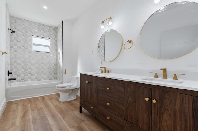 full bathroom featuring vanity, hardwood / wood-style flooring, tiled shower / bath, and toilet