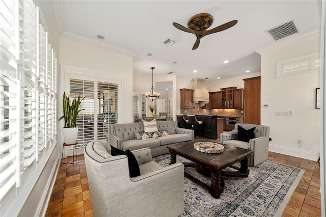 living room with ornamental molding, dark parquet flooring, and ceiling fan with notable chandelier