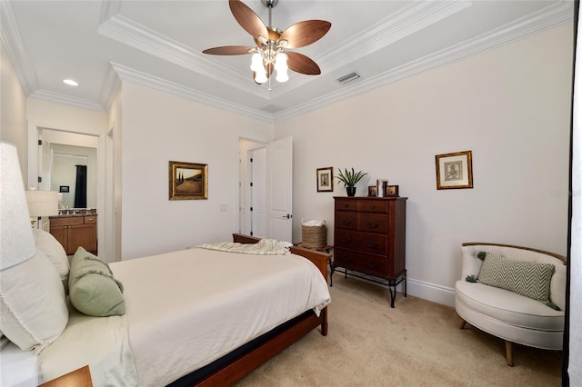 bedroom with light carpet, a tray ceiling, crown molding, ensuite bathroom, and ceiling fan