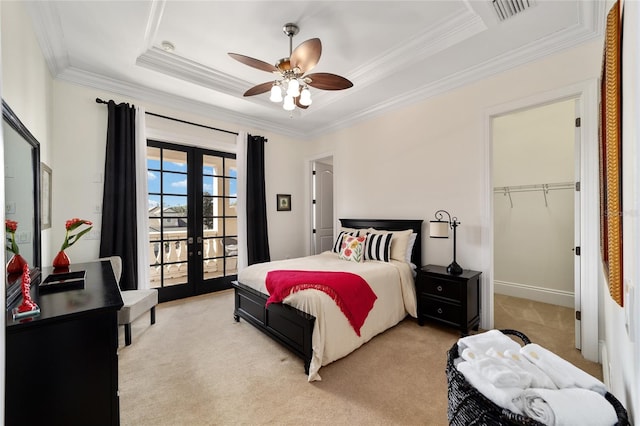 bedroom featuring a raised ceiling, a walk in closet, ceiling fan, french doors, and light colored carpet