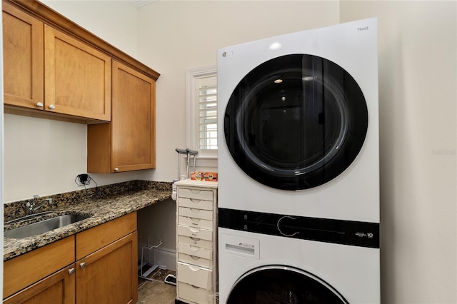 laundry room with stacked washer / dryer, cabinets, and sink