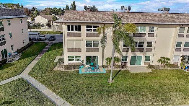 rear view of property featuring a lawn and a patio area