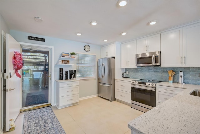 kitchen with white cabinets, a wealth of natural light, light stone counters, and appliances with stainless steel finishes