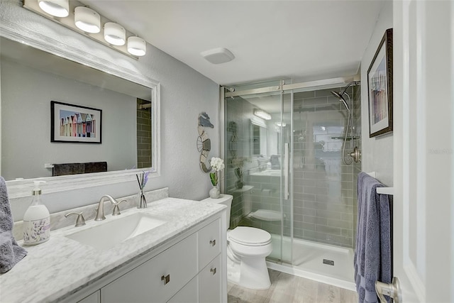 bathroom featuring vanity, wood-type flooring, an enclosed shower, and toilet