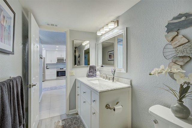 bathroom featuring tile patterned flooring, vanity, and toilet