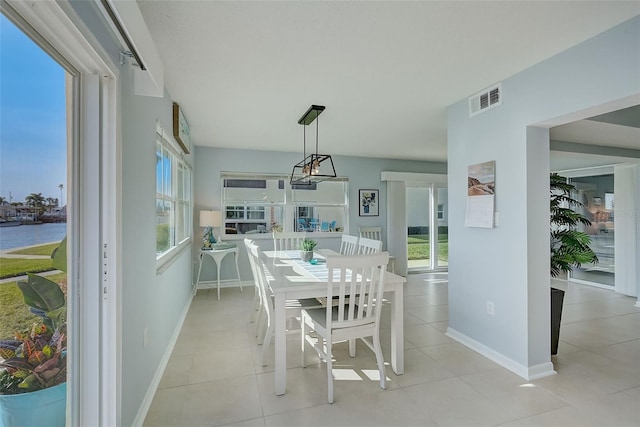 dining area with a water view and light tile patterned floors