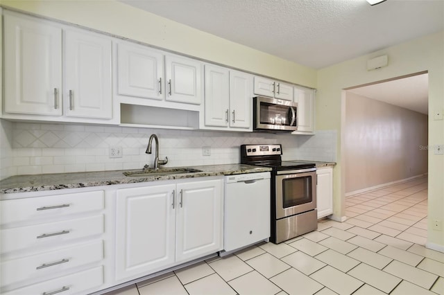 kitchen with white cabinetry, stainless steel appliances, sink, and dark stone countertops