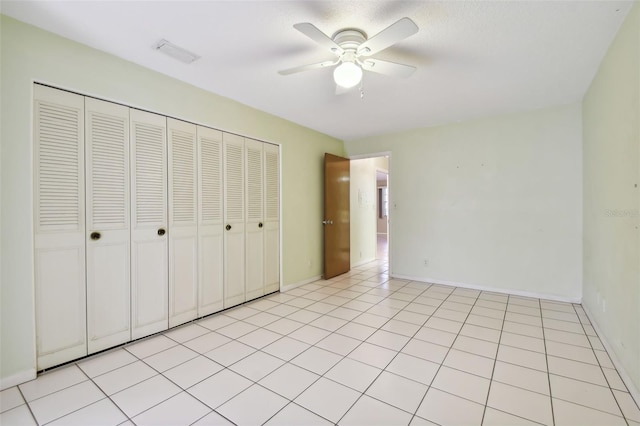 unfurnished bedroom with light tile patterned floors, a closet, and ceiling fan