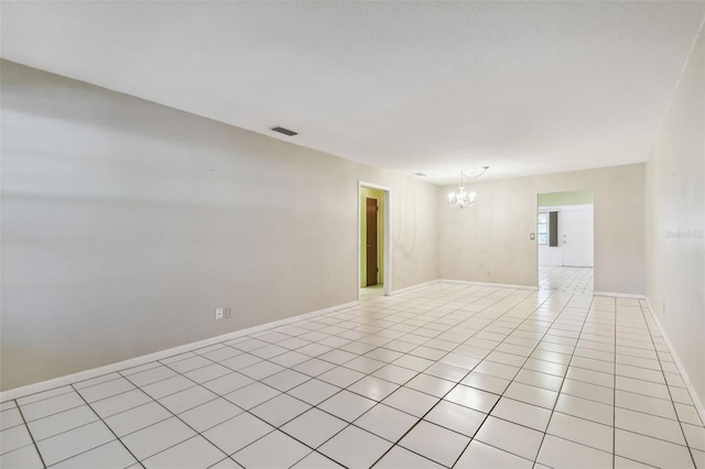 tiled empty room with an inviting chandelier