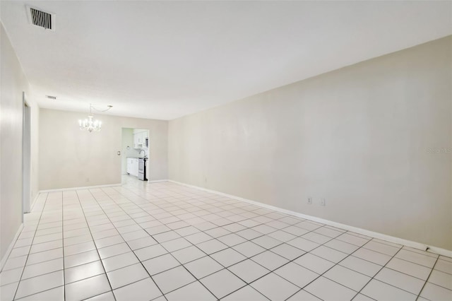 tiled empty room featuring an inviting chandelier