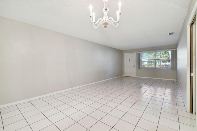 empty room featuring light tile patterned flooring, a textured ceiling, and an inviting chandelier