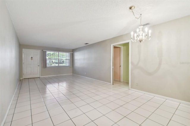 empty room with light tile patterned floors and an inviting chandelier