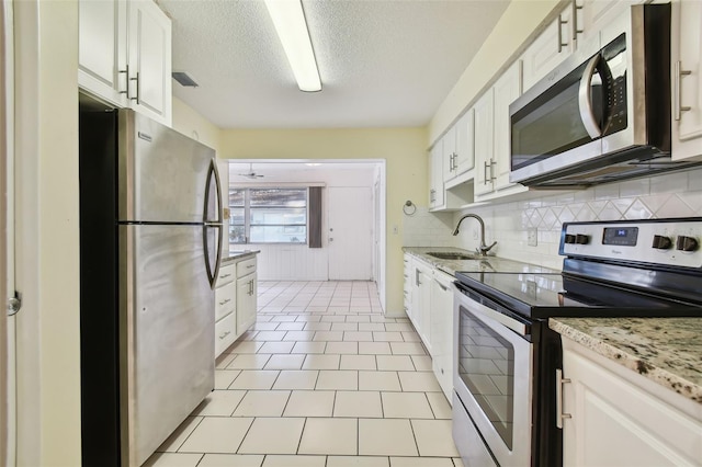 kitchen with appliances with stainless steel finishes, white cabinetry, sink, and light stone counters