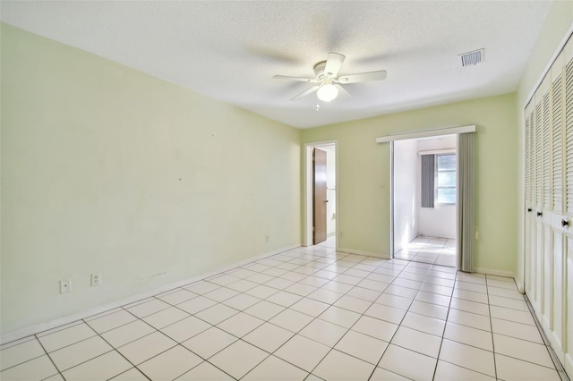 unfurnished bedroom with light tile patterned floors, a textured ceiling, a closet, and ceiling fan