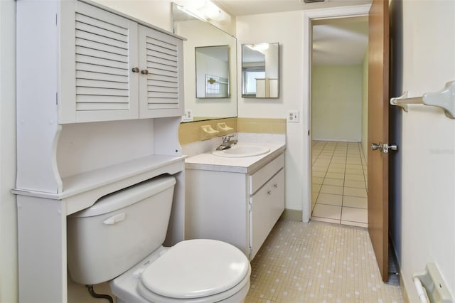 bathroom with toilet, vanity, and tile patterned flooring