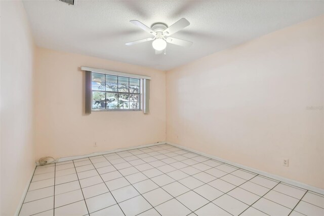 empty room featuring ceiling fan, a textured ceiling, and light tile patterned flooring