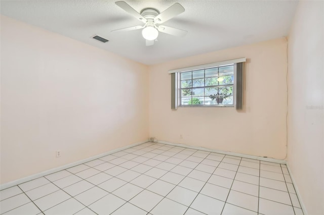 spare room featuring a textured ceiling, light tile patterned flooring, and ceiling fan