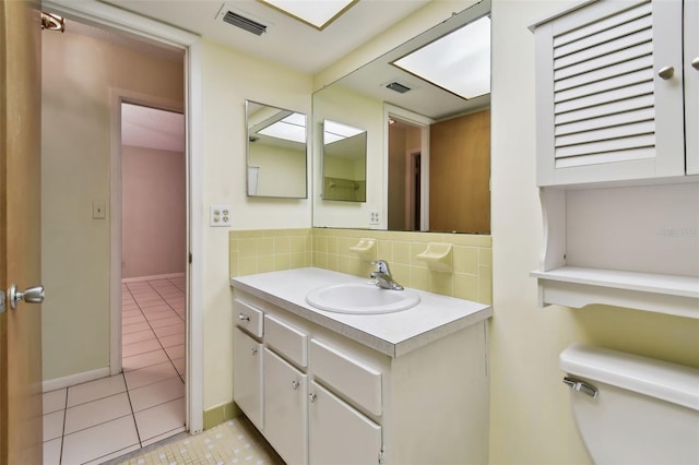 bathroom featuring toilet, tasteful backsplash, vanity, and tile patterned flooring