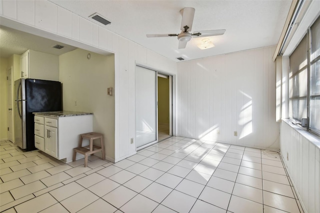 kitchen featuring stainless steel refrigerator, white cabinetry, ceiling fan, and a wealth of natural light