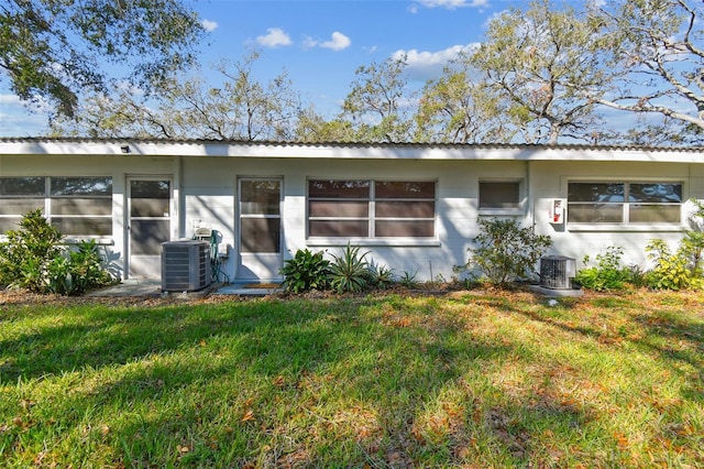 rear view of property featuring central air condition unit and a yard