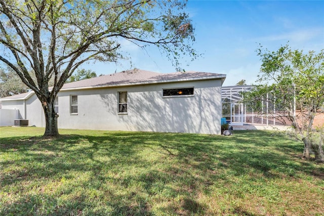 back of house featuring central air condition unit, a lawn, and a lanai