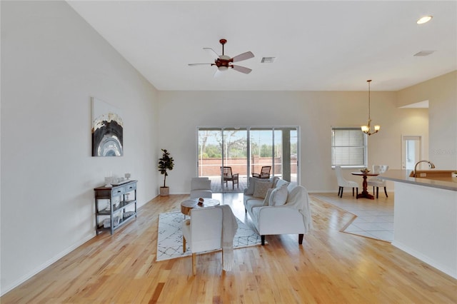 living room featuring light wood-type flooring and ceiling fan with notable chandelier