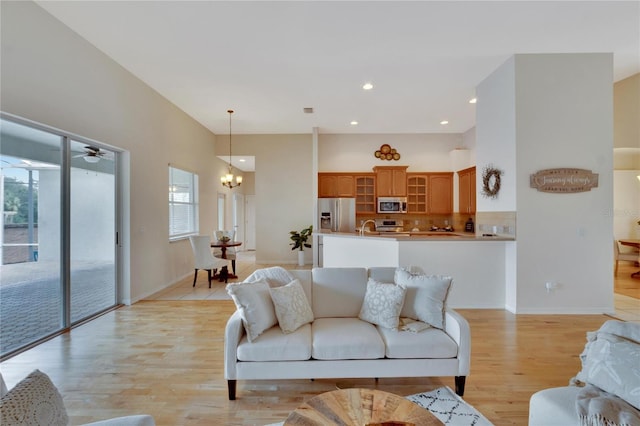 living room with sink, light hardwood / wood-style flooring, and ceiling fan with notable chandelier