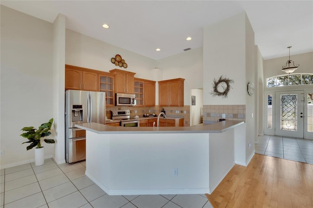 kitchen with light wood-type flooring, appliances with stainless steel finishes, sink, and kitchen peninsula