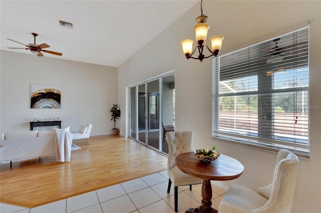 dining space featuring vaulted ceiling, ceiling fan with notable chandelier, and hardwood / wood-style floors