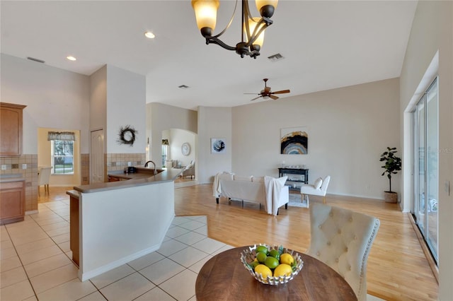 kitchen featuring light hardwood / wood-style flooring, decorative light fixtures, ceiling fan with notable chandelier, and kitchen peninsula