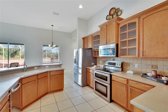 kitchen with sink, decorative light fixtures, light tile patterned floors, appliances with stainless steel finishes, and tasteful backsplash