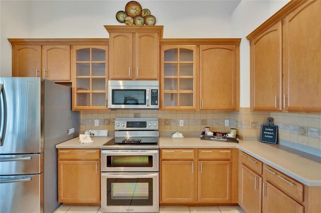 kitchen with light tile patterned flooring, tasteful backsplash, and stainless steel appliances