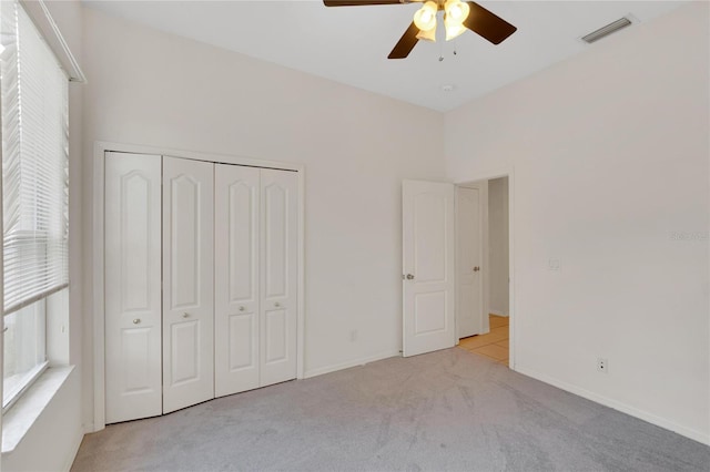 unfurnished bedroom with a closet, light colored carpet, and ceiling fan