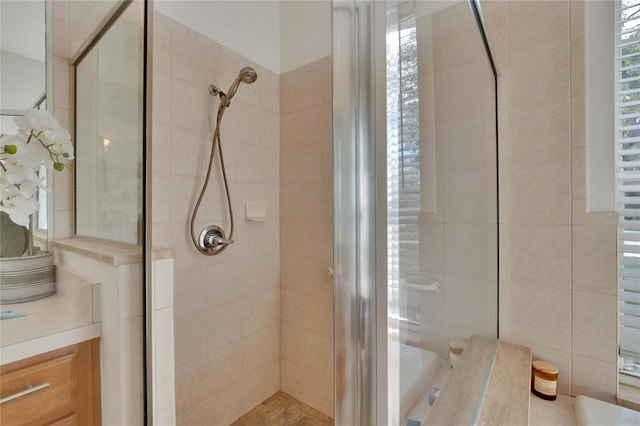 bathroom featuring a shower with door and vanity