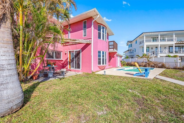 rear view of house featuring a lawn, a patio area, a balcony, and a fenced in pool