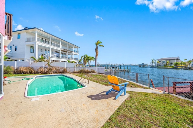 view of swimming pool featuring a water view, a patio area, and a lawn